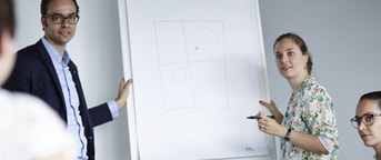 Mitarbeitende vor Flipchart Mitarbeitende vor Flipchart